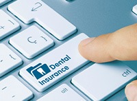 A finger pressing a ‘Dental Insurance’ key on a keyboard
