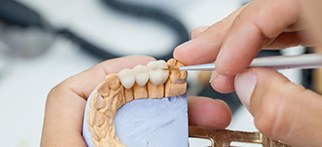 Dental lab technician carefully working on bridge