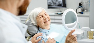 Older woman examining her dental implants in Allentown