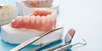 a model of dentures in Allentown sitting next to dental tools