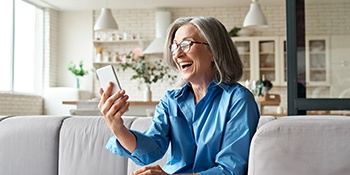 a smiling person video chatting with their friend while sitting on a couch