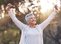 Woman in pink jacket with arms outstretched outside