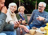 Four adults chatting and laughing over coffee and donuts