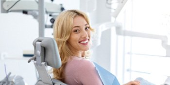 Blonde woman sitting in dental chair and smiling