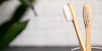 Close-up of two toothbrushes in a clear glass