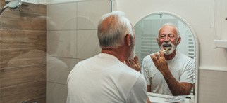 man brushing his teeth in front of a mirror