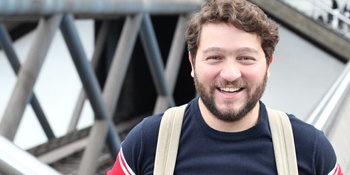 student holding their backpack and smiling