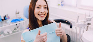 Woman in dental chair giving thumbs up