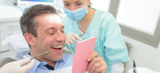 Man in dental chair looking at smile in mirror