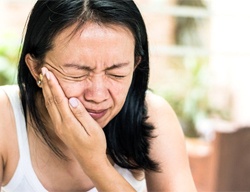 woman holding mouth in pain 