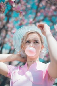 woman under cherry blossom tree chewing bubble gum