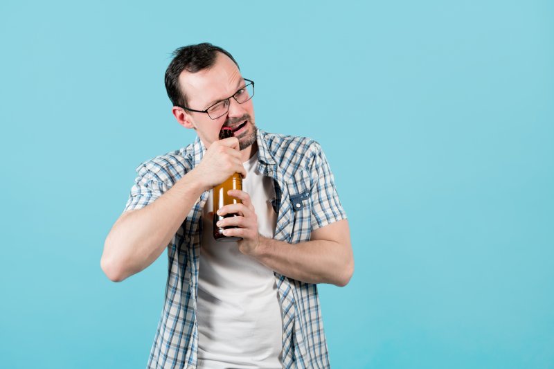 person opening a bottle with their teeth