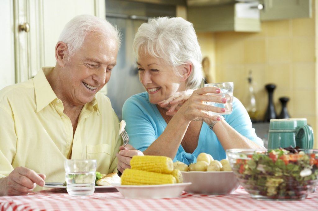 Older couple enjoying food with implant dentures.