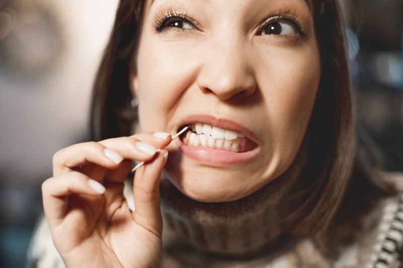 a woman using a toothpick and wincing