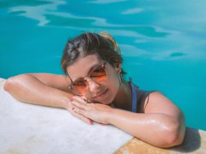 Young woman resting her head on the edge of a pool